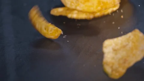 Fresh roasted potato chips falling on black surface Stock Footage 90964649