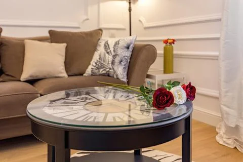 Fresh roses on coffee table with clock inside. Interior of living room with cosy Photos