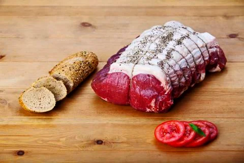 Fresh round tip roast with bread and tomato on wood background. food 写真素材