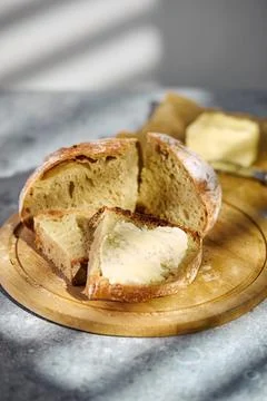 Fresh rustic bread slice with butter on wooden cutting board Stock Photos