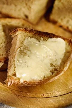 Fresh rustic bread slice with butter on wooden cutting board Stock Photos