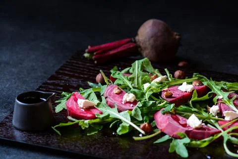 Fresh salad from beetroot, cheese and rocket salad on black wood background Stock Photos