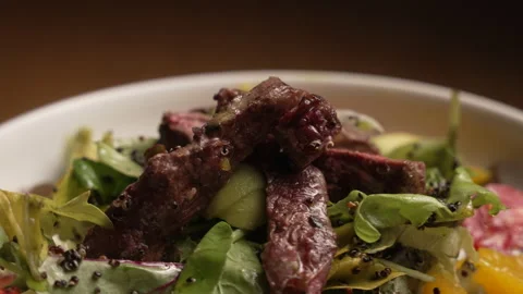 A fresh salad with grilled beef steak, tomatoes, greens, and quinoa seeds 動画素材 335378913