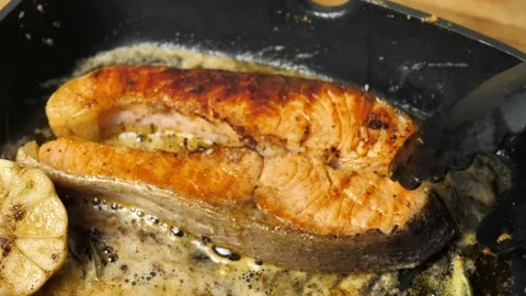 Fresh salmon steak is put on a hot grill pan for cooking.close-up Stock Footage 214419083