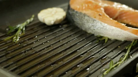 Fresh salmon steaks being placed on a hot grille to cook, close-up Stock Footage 97798948