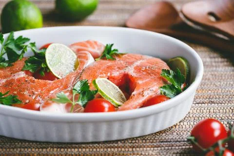 Fresh salmon steaks with lime, cherry tomatoes, parsley and olive oil Stock Photos