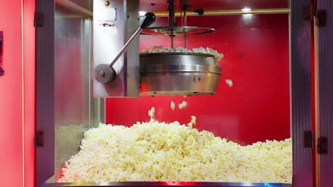 Fresh salted popcorn fall from hot kettle into display case of  popcorn mac.. Stock Footage 338189316