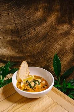 Fresh seafood stew with bread served on a wooden table in a tropical setting Stock Photos