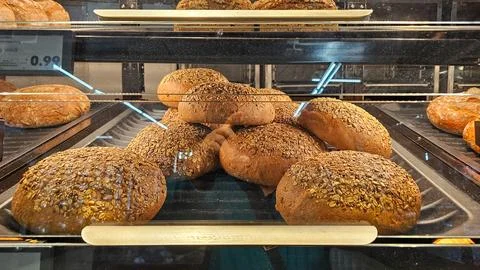 Fresh seeded bread buns in bakery display case Stock Photos