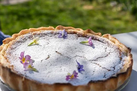 Fresh self made easter pie on table with flower decoration into garden. Stock Photos