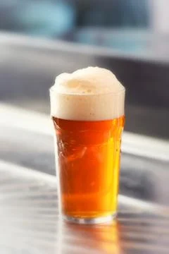 Fresh served pint of frothy draft beer in a glass Stock Photos