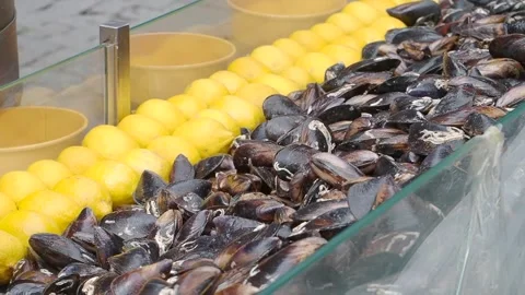 Fresh shellfish and lemons at a market stall in a coastal town Stock Footage 346339602