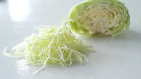Fresh shredded cabbage with a halved cabbage placed on a clean white surface Stock Footage 337976659