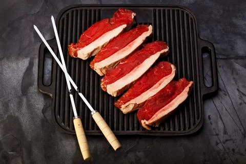 Fresh silver side tip steak on grill with metal skewers. food Stock Photos