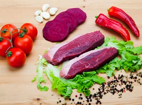 Fresh silver side tip steak with vegetables on wood background. food Stock Photos