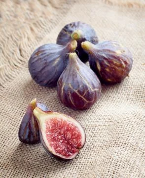 Fresh slice of fig lying on a heap of ripe figs. Heap of tasty organic figs Stock Photos