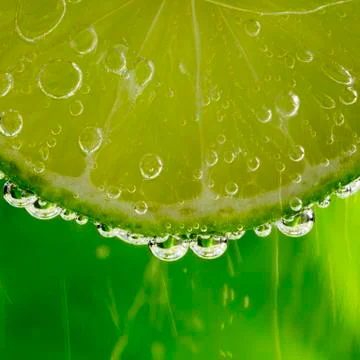 Fresh slice of lime in the water with bubbles Stock Photos