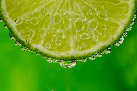 Fresh slice of lime in the water with bubbles Stock Photos