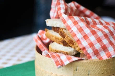 Fresh sliced bread wrapped in a checkered red and white napkin inside woode.. Stock Photos