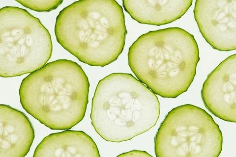Fresh sliced cucumbers in symmetrical pattern, vibrant green color, white p.. Stock Photos
