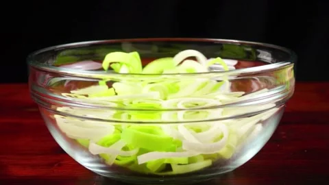 Fresh sliced leek rings falling into transparent glass bowl slow motion. Stock Footage 336329104