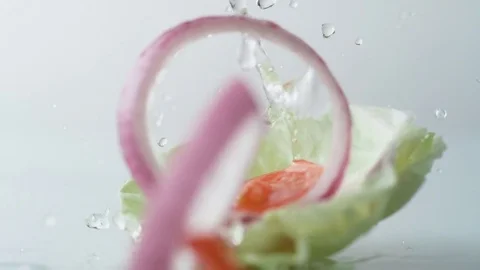 Fresh sliced vegetables falling on water surface. Slow Motion. Stock Footage 79478954