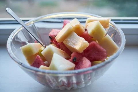 Fresh sliced watermelon and melon in a glass bowl with a small spoon Stock Photos