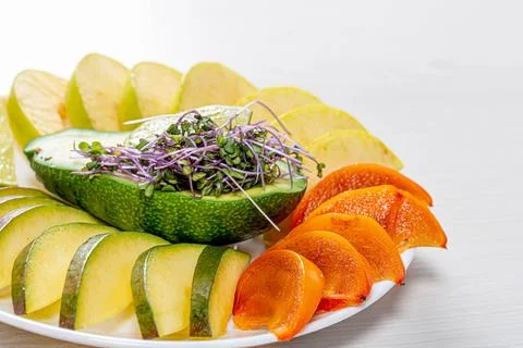 Fresh slices of mango, persimmon, Apple, lime and avocado with micro greens Stock Photos