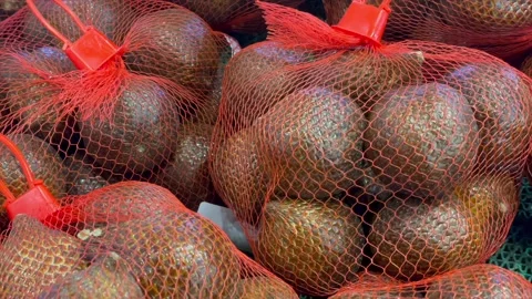 Fresh snake fruit in red mesh bags at market Видео 340485730