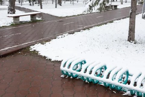 Fresh snow on paved path, bench and lawns Stock Photos