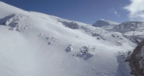 Fresh snow steep slope through rocks over ridge with cable ski lift Stock Footage 104654644