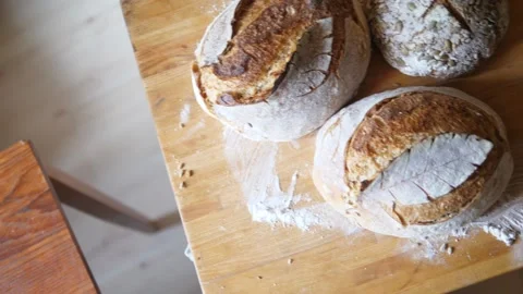Fresh sourdough bread on kitchen table birdseye pan right rotating Stock Footage 196000193
