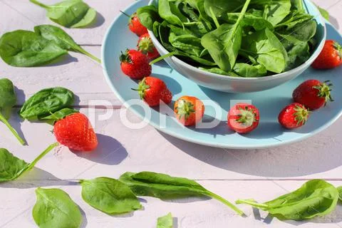 Fresh Spinach Salad With Spinach And Strawberries On Wooden Light Pink Table