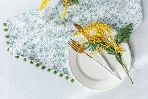 Fresh spring table setting with mimosa flowers and golden utensils Foto stock
