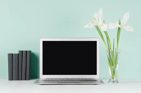 Fresh spring workplace for work and study with blank laptop display, black bo Stock Photos