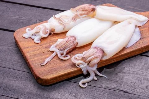 Fresh squid or raw squid on a wooden board Seafood menu on wooden backgroun.. Stock Photos