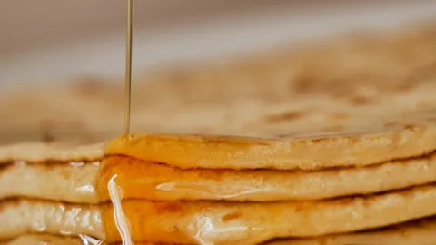 Fresh stacked pancakes is doused with maple syrup - sweet delicious breakfast Stock Footage 153669747