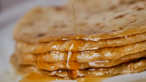 Fresh stacked pancakes is doused with maple syrup - sweet delicious breakfast Stock Footage 153671873