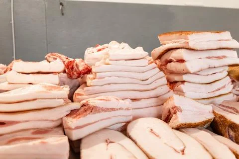 Fresh stacks of raw pork fat and bacon are displayed at a local market stal.. Stock Photos