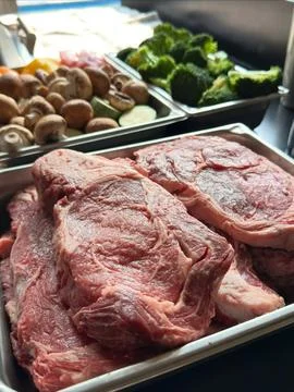 Fresh steaks prepared alongside assorted vegetables Stock Photos