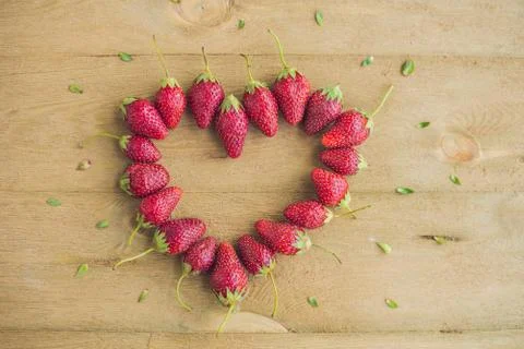 Fresh strawberries array heart shape on old wooden background Stock Photos