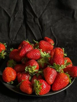 Fresh strawberries on black background with dramatic lighting and rich colors Stock Photos