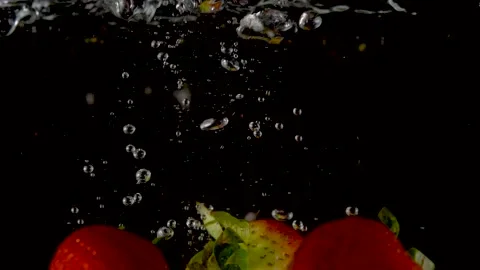Fresh Strawberries falling into clear water with big splash on black background. Vídeo Stock 150567123