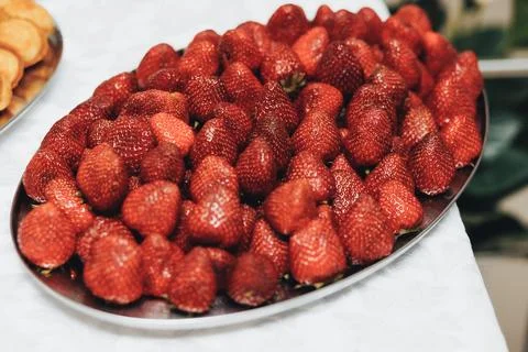 Fresh strawberries fill a shiny oval platter Stockfoto's