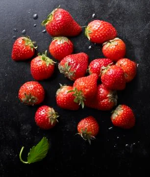 Fresh strawberries with a leaf on a black baking tray Stock Photos