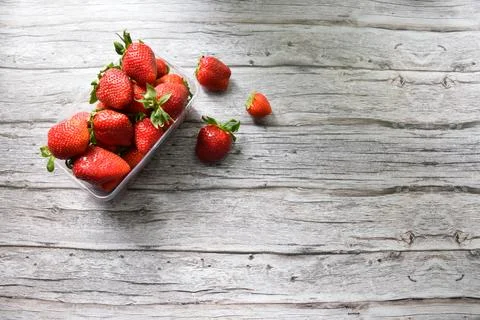 Fresh Strawberries in Plastic Container on Light Wooden Background Stock Photos