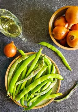 Fresh string beans, onions and olive oil on a dark background. Stock Photos