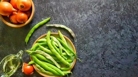 Fresh string beans, onions and olive oil on a dark background with copyspace. Stock Photos