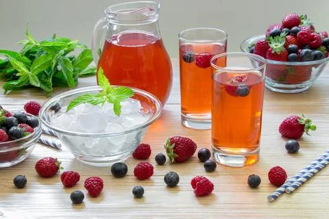Fresh summer beverage display featuring mixed berry drinks, ice, and mint leaves Stock Photos