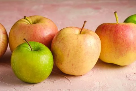 Fresh sweet apples on pink textured background, angle view macro Stock Photos